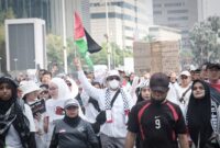 Sahrul Gunawan dengan membawa bendera Palestina tampak hadir berjalan ditengah lautan peserta aksi Palestina menuju Lapangan Monas Jakarta. Minggu (5/11/2023)