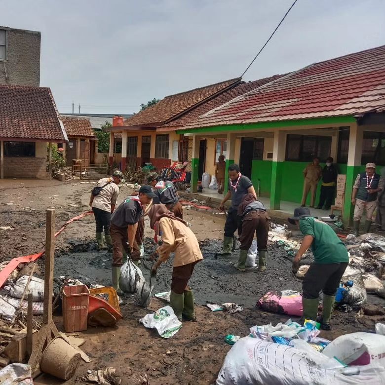 Pramuka Peduli Kwarcab Kabupaten Bandung berjibaku bersama relawan lain memebersihkan lumpur di SDN 01 Baturengat dan permukiman di Kampung Blok Hawu, Desa Cigondewah Hilir, Kecamatan Margaasih, akibat terendam banjir, Rabu (6/12/2023).